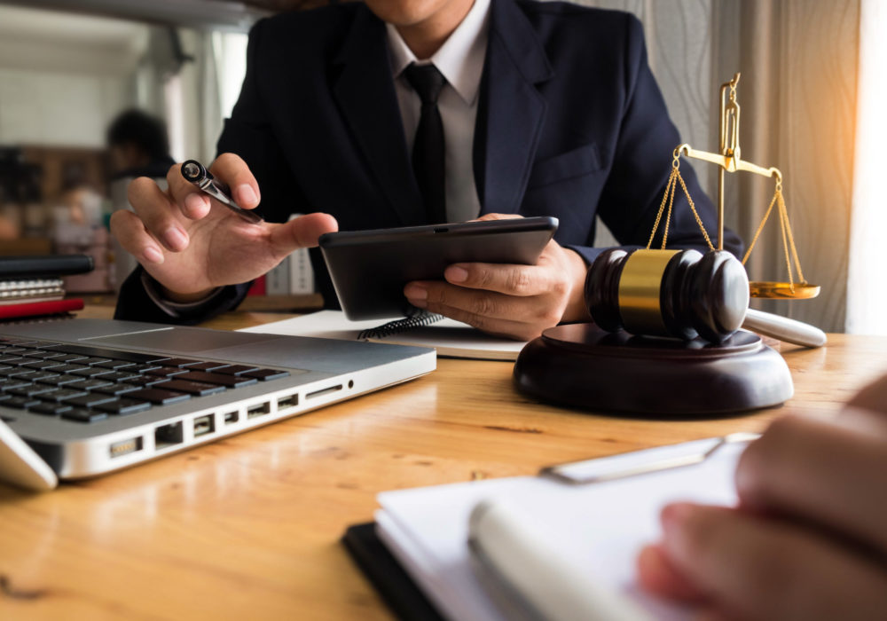 Attorney working at desk with tablet computer and laptop with client