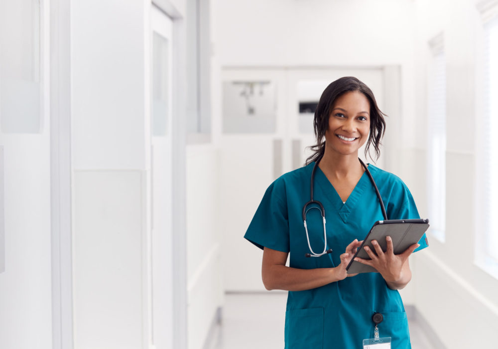 Nurse smiling in hallway with tablet